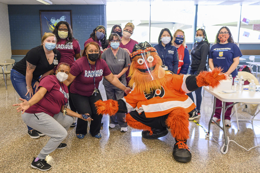 Volunteers at a Penn Medicine/Delaware County vaccination event at Radnor High School pose for a group photo together with Flyers mascot Gritty.